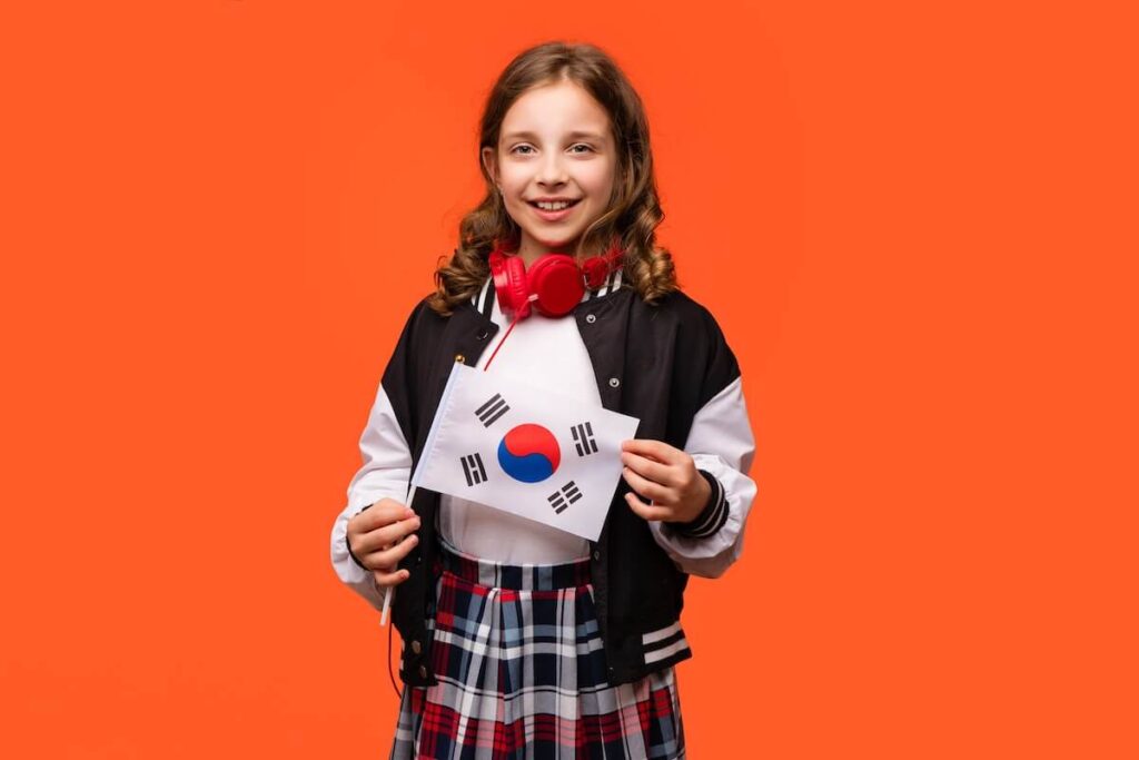 girl in school outfit and red headphones holds small national flag of South Korea