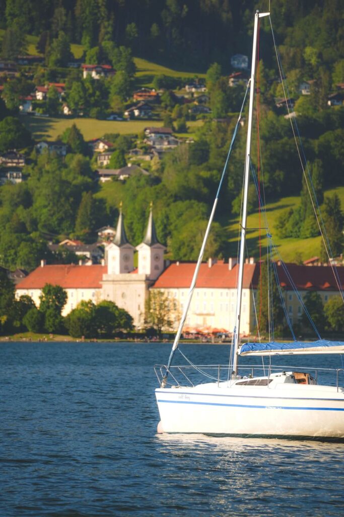 Serene view of a sailboat on Lake Tegernsee with the historic monastery in the background, Bavaria, Germany