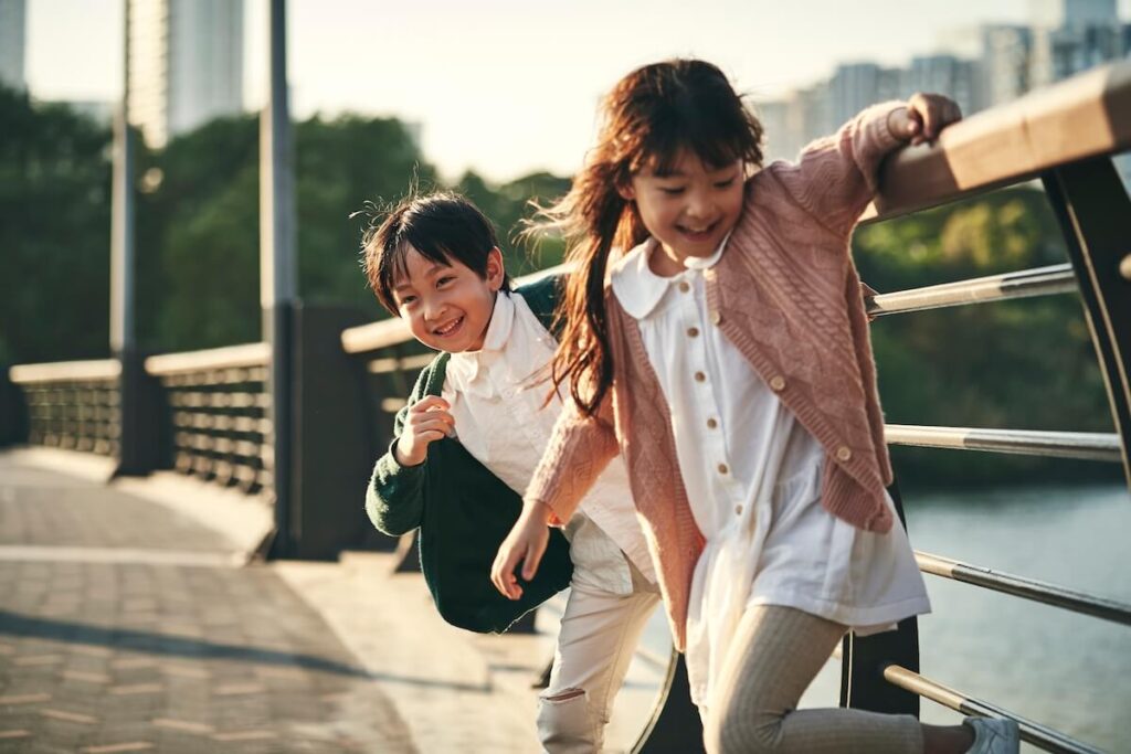two happy asian children having good time playing in city park