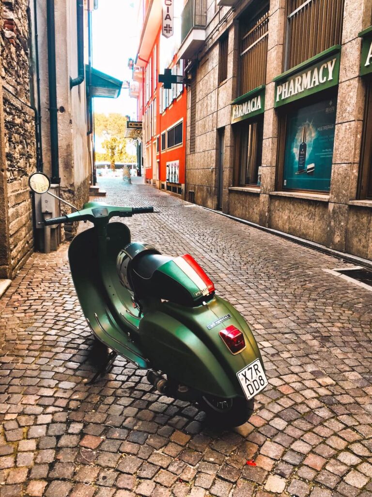 a green Vespa parked in a street in Stresa, Italy