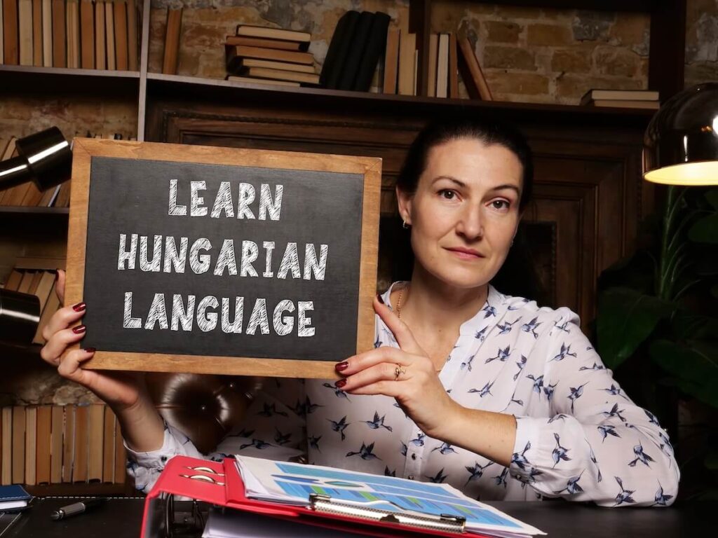 woman holding up board that says "Learn Hungarian Language"