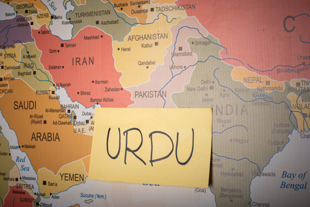 Urdu word written on a sticky note with Pakistan map in the background