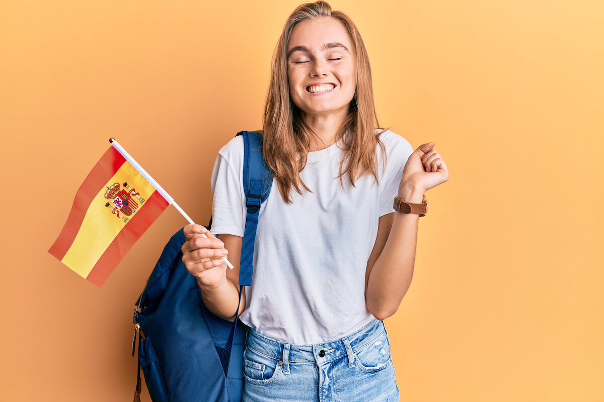 female student smiling while holding Spanish flag
