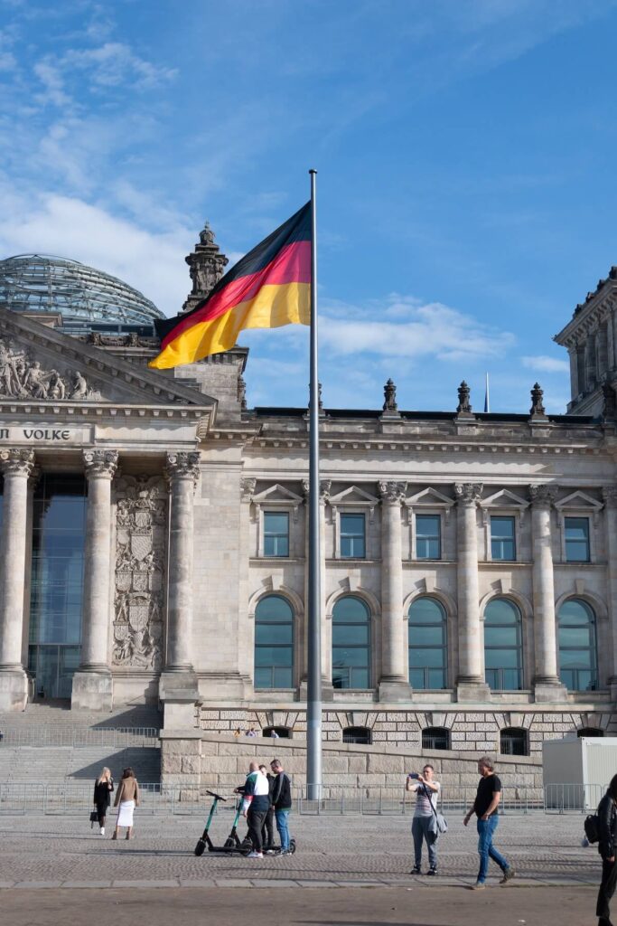 tourists near building in Berlin with German flag waving