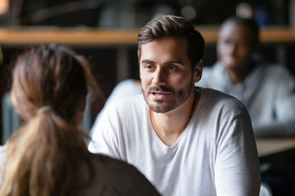Young serious man having conversation with woman