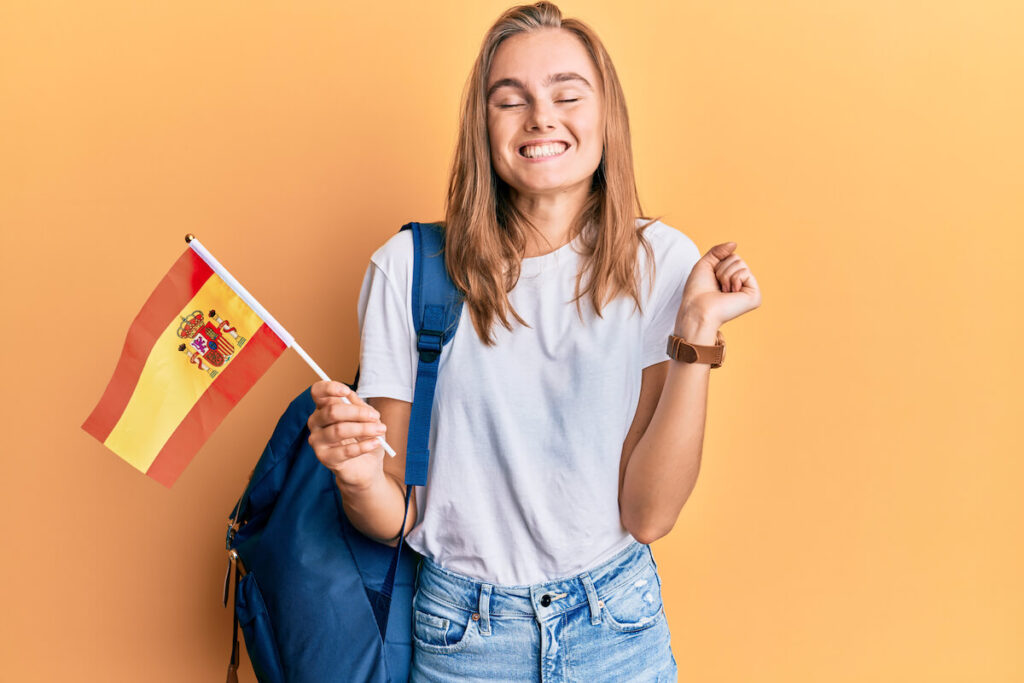 student holding spanish flag screaming proud