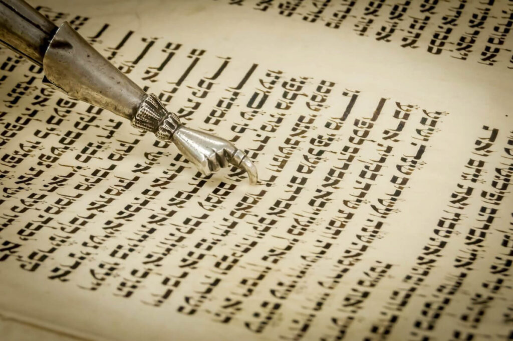 Torah "yad" pointer and the ancient Hebrew text of the Book of Genesis in the Torah scroll