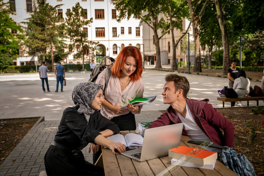 Students study together, chat, look at the computer and laugh in the garden of the school