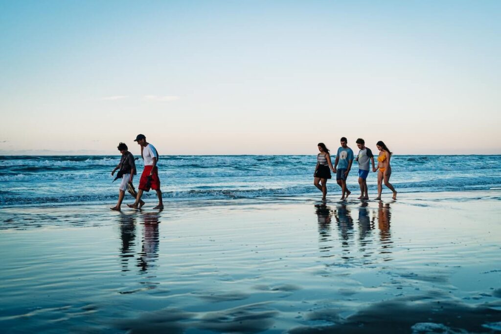 People of all ages stroll along the beach in Vieste, Puglia, Italy, during blue hour