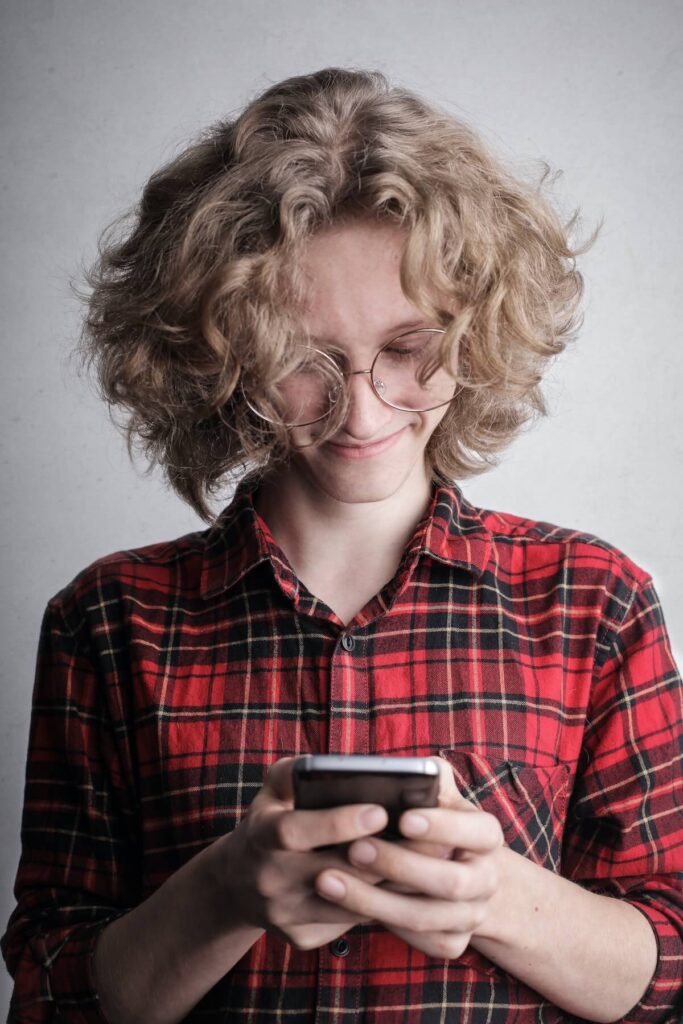Photo of Smiling Person in Red and Black Plaid Shirt using phone