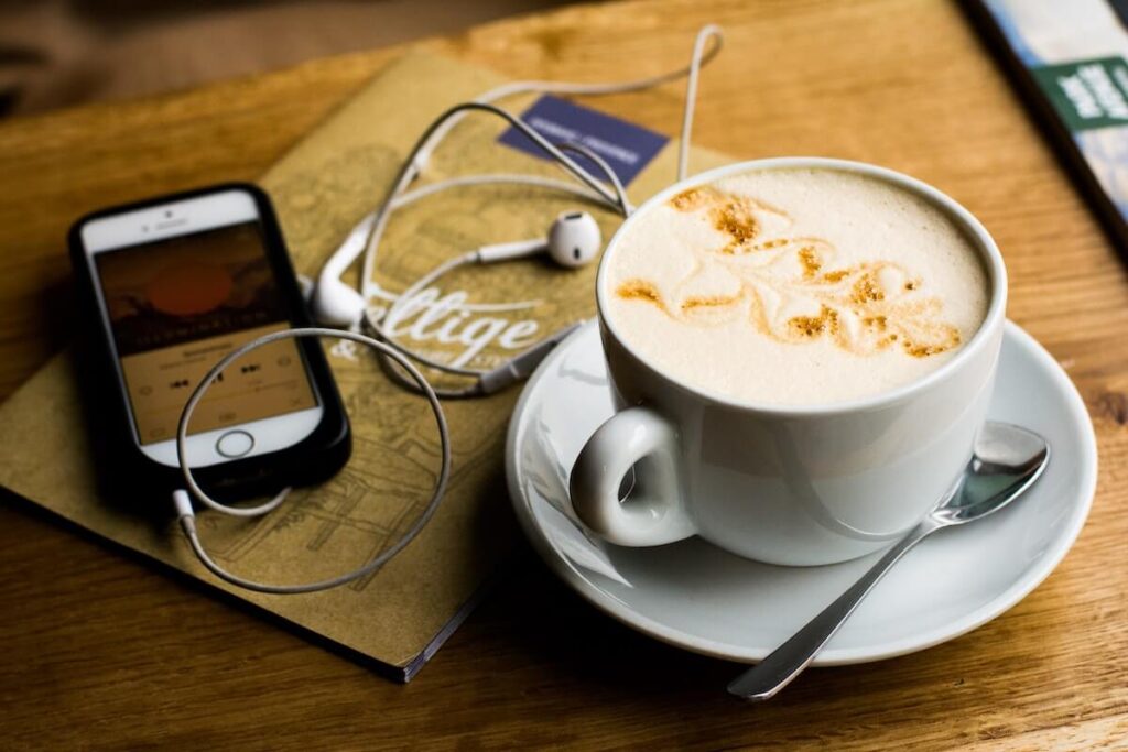 phone, coffee, earphones, and book on table