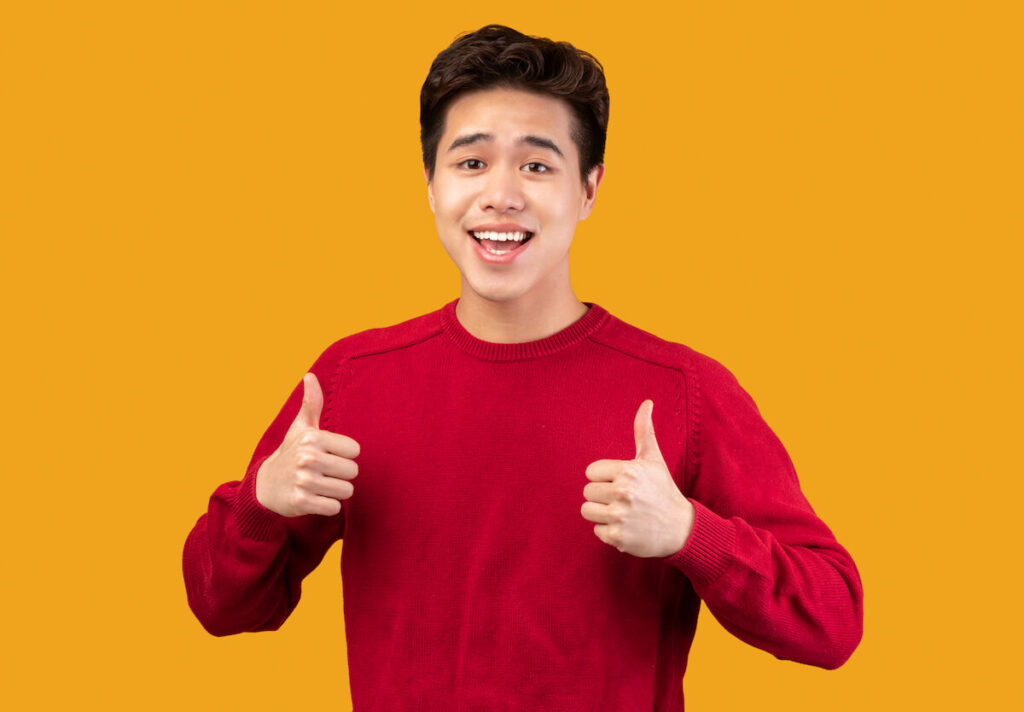 happy man showing thumbs up, doing approval gesture with fingers and both hands