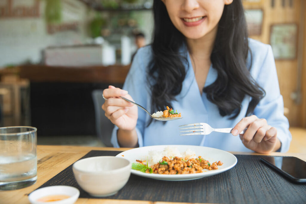 Close up of young woman eating Thai food in restaurant