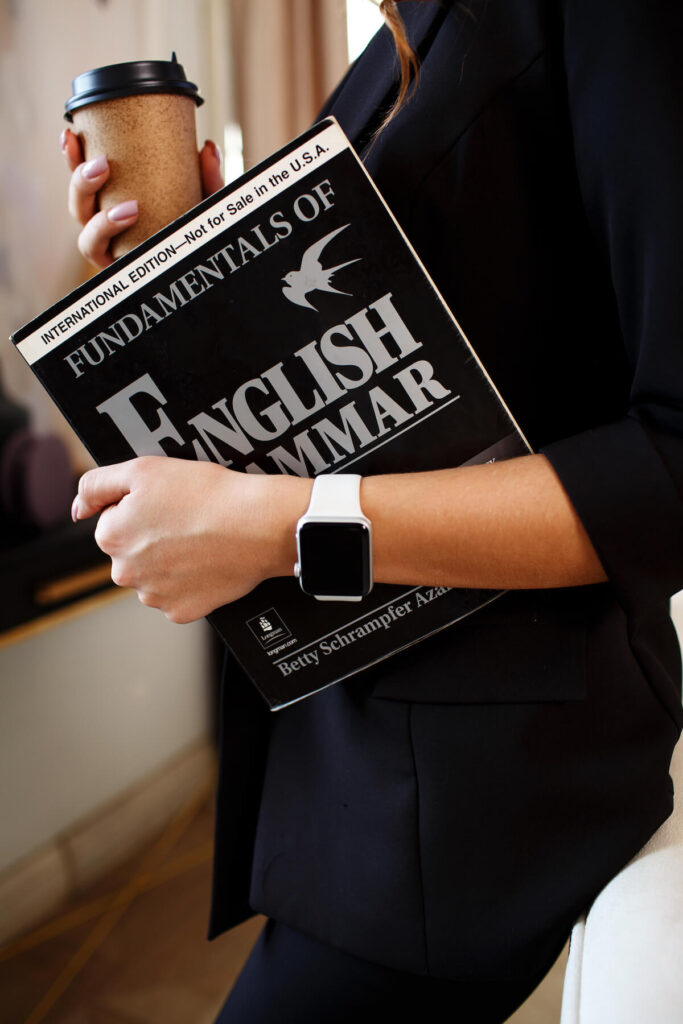 A woman holds books and educational materials in English