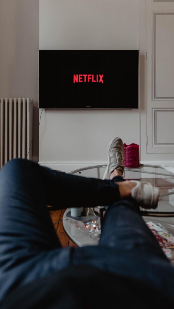 netflix on tv monitor and person relaxing