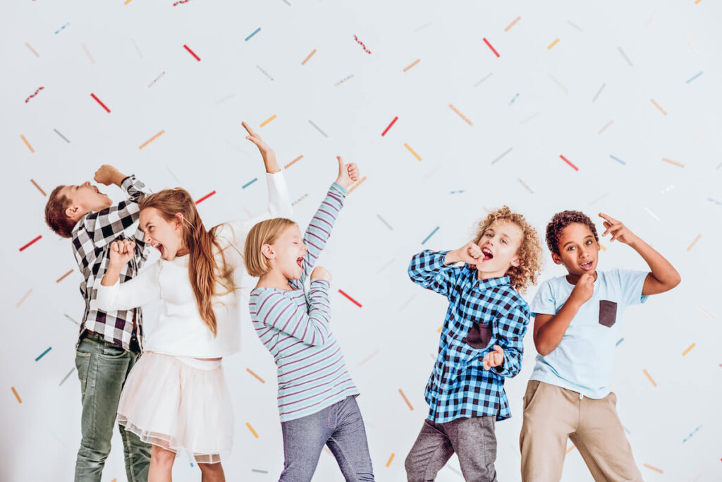 Group of happy boys and girls pretending to sing at a party