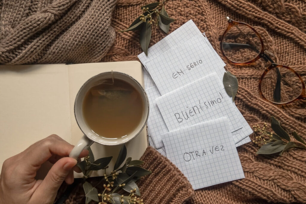 A cup of tea with some flash cards of vocabularies in Spanish on brown background for Spanish learners