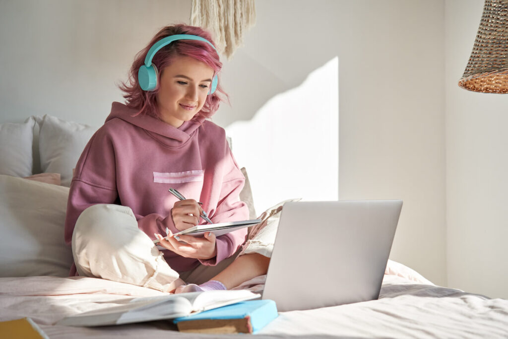 student with pink hair wear headphone write notes