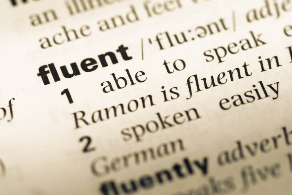 Close up of old English dictionary page with word fluent