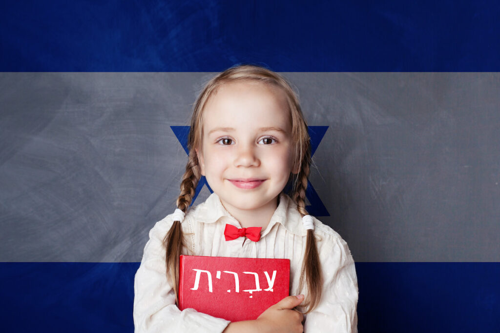girl holding Hebrew book, with Israel flag in the background