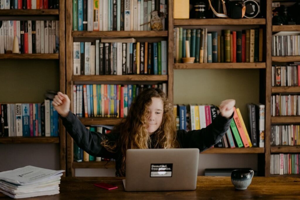 girl celebrates in front of computer