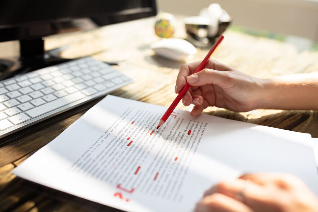 Close up of a person's hand marking error with red marker on document