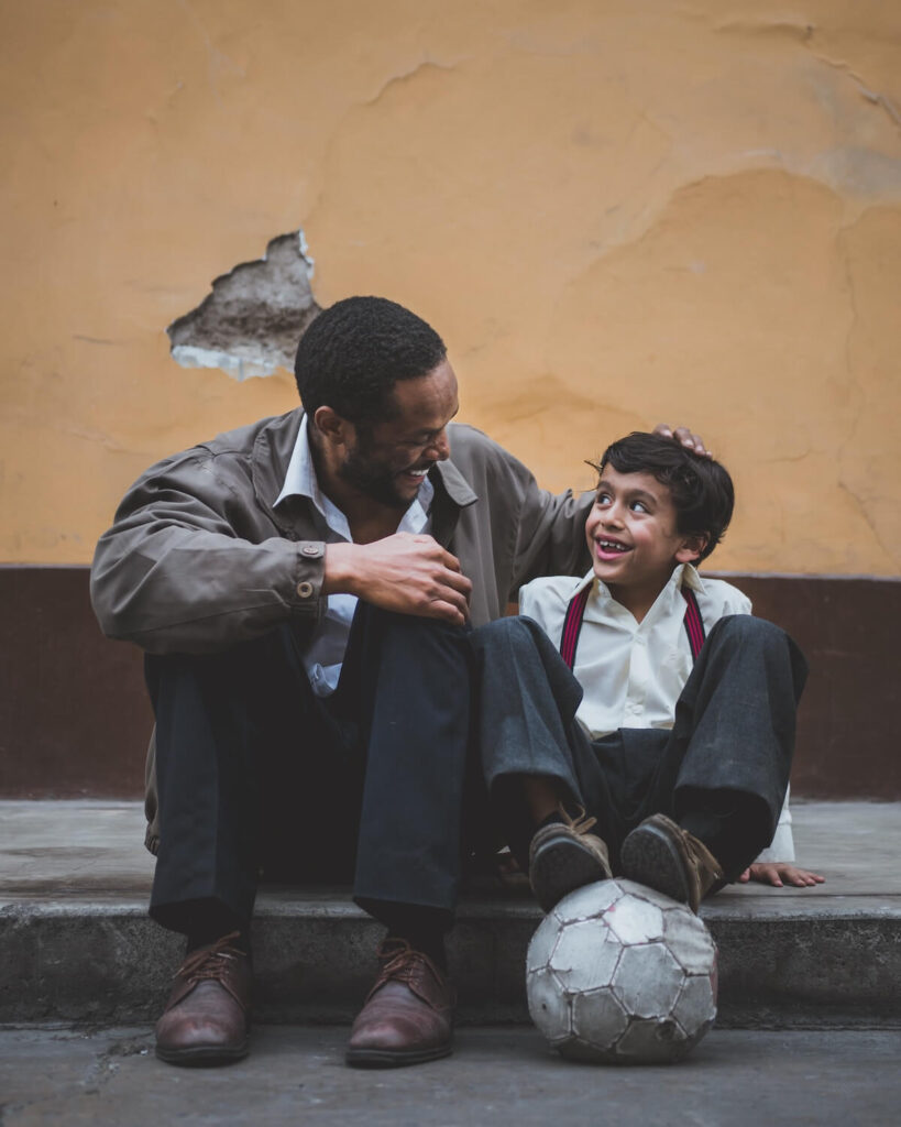 father and son interact over soccer ball