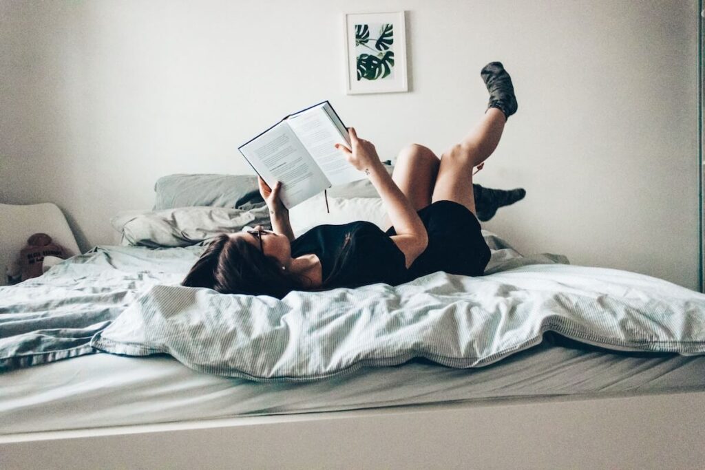 woman reading book in bed