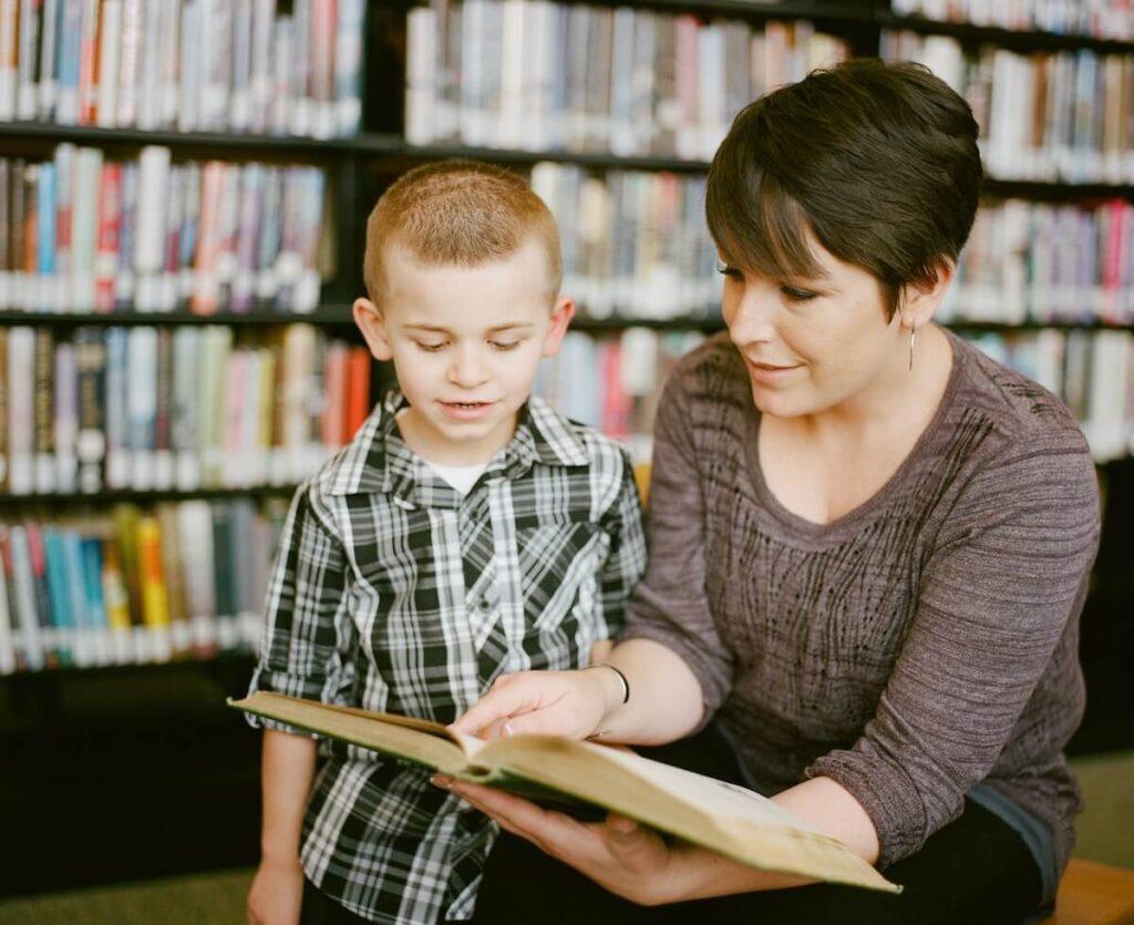 woman helps boy read book