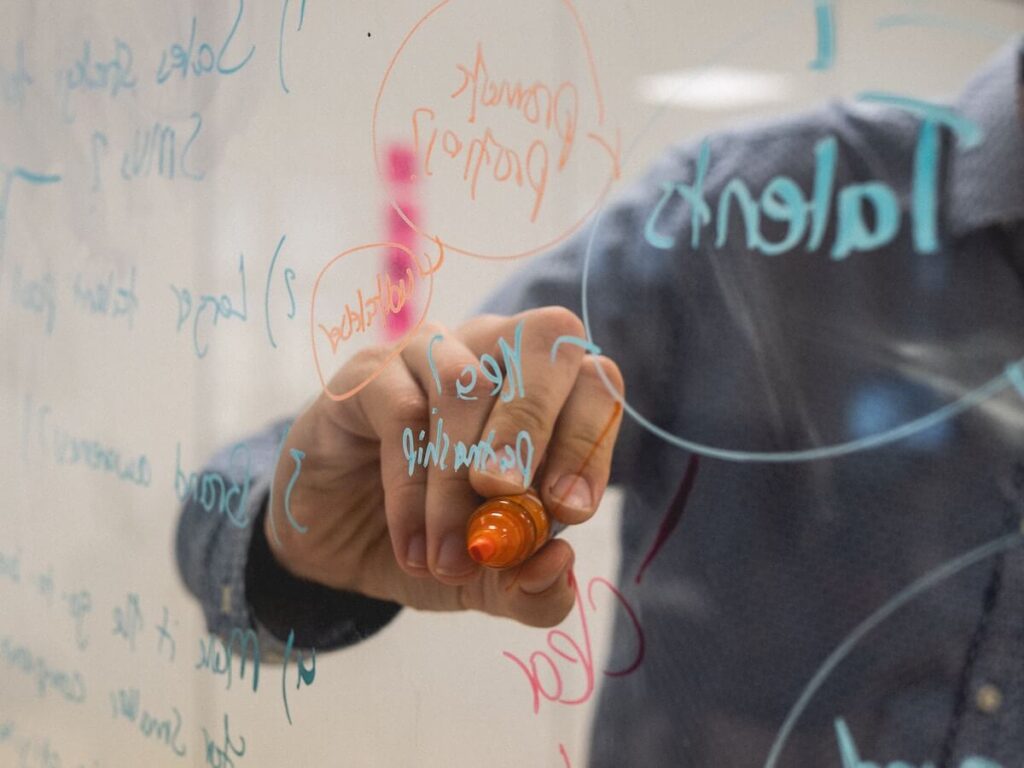 person writing on glass whiteboard