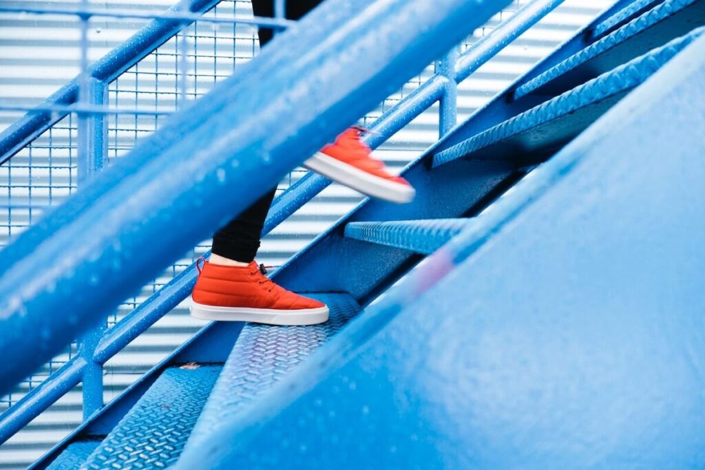 person walking up blue metal stairs