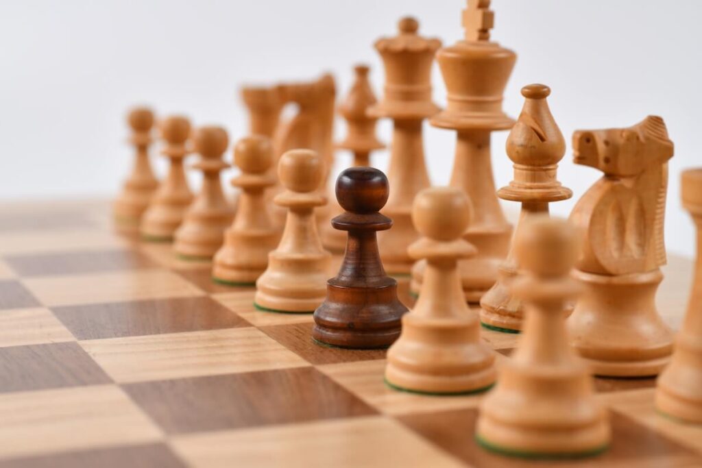 dark pawn amid light colored chess pieces