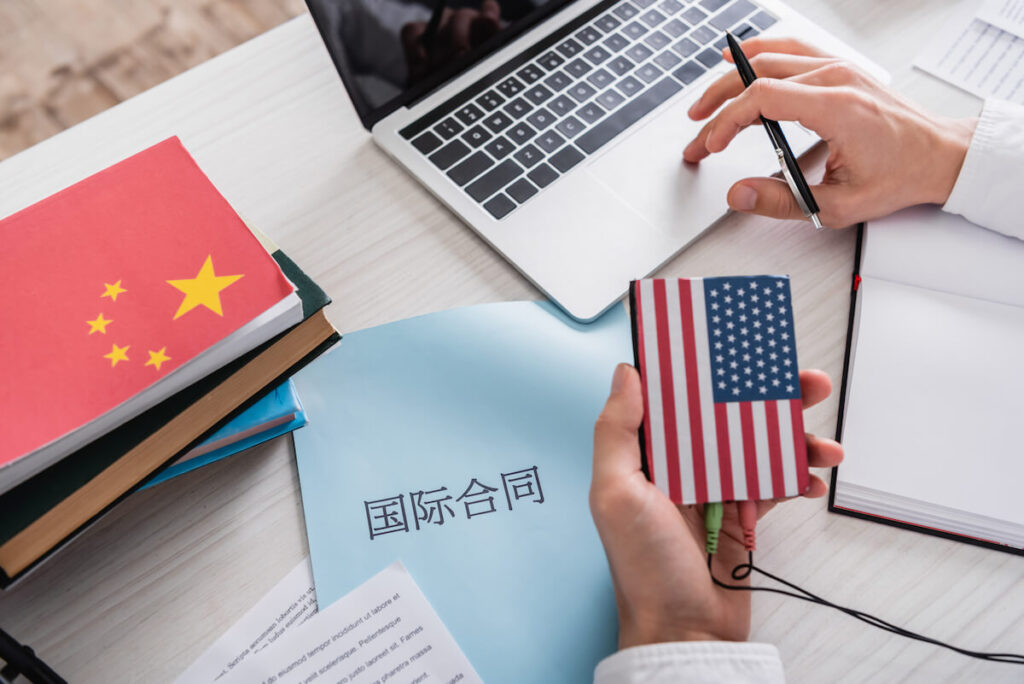 person working on desk amid Chinese characters and US and China flags