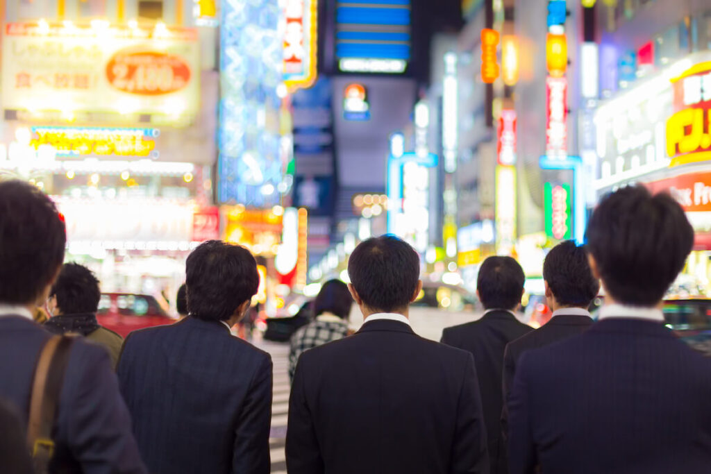 Japanese business people in suits, waiting during rush hour on a crossroad in Shinjuku business district, Tokyo, Japan