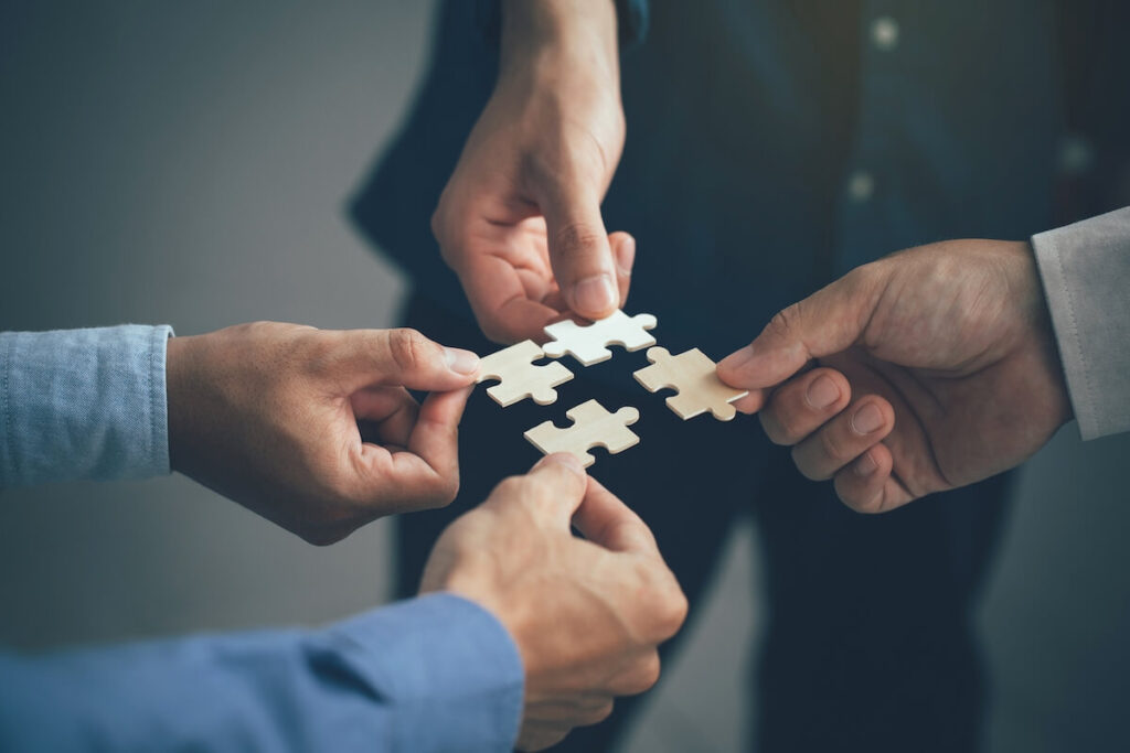four people joining jigsaw puzzle pieces