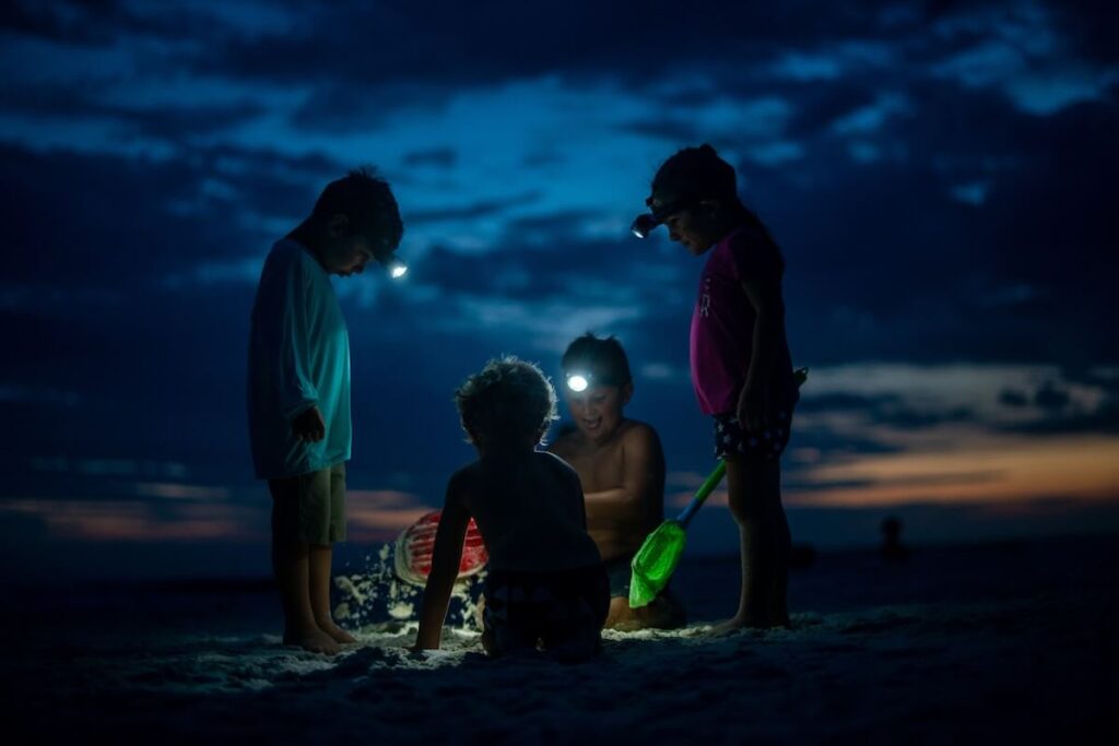 four kids digging in the sand at dusk