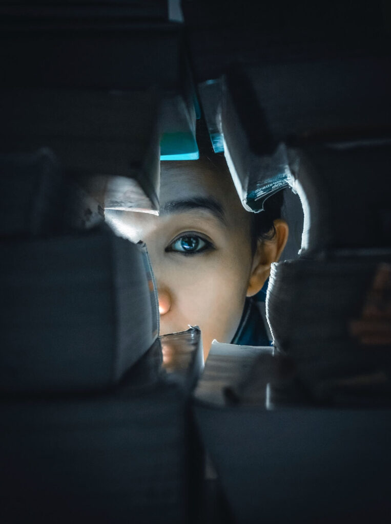 woman looking through hole on stack of books