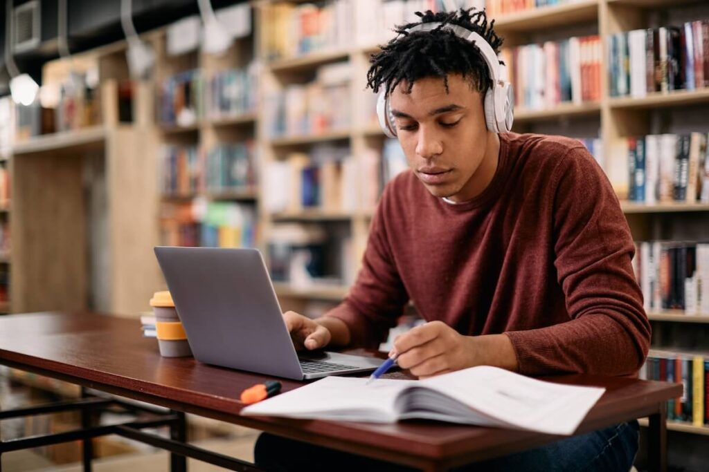 student studying with a book and laptop in a library