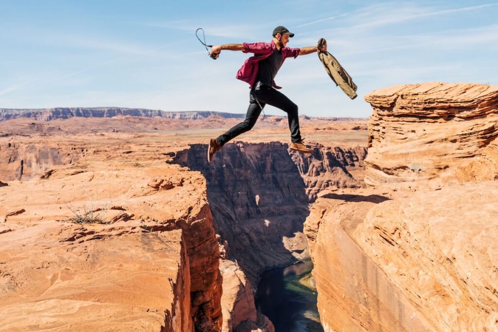 man jumping between cliffs