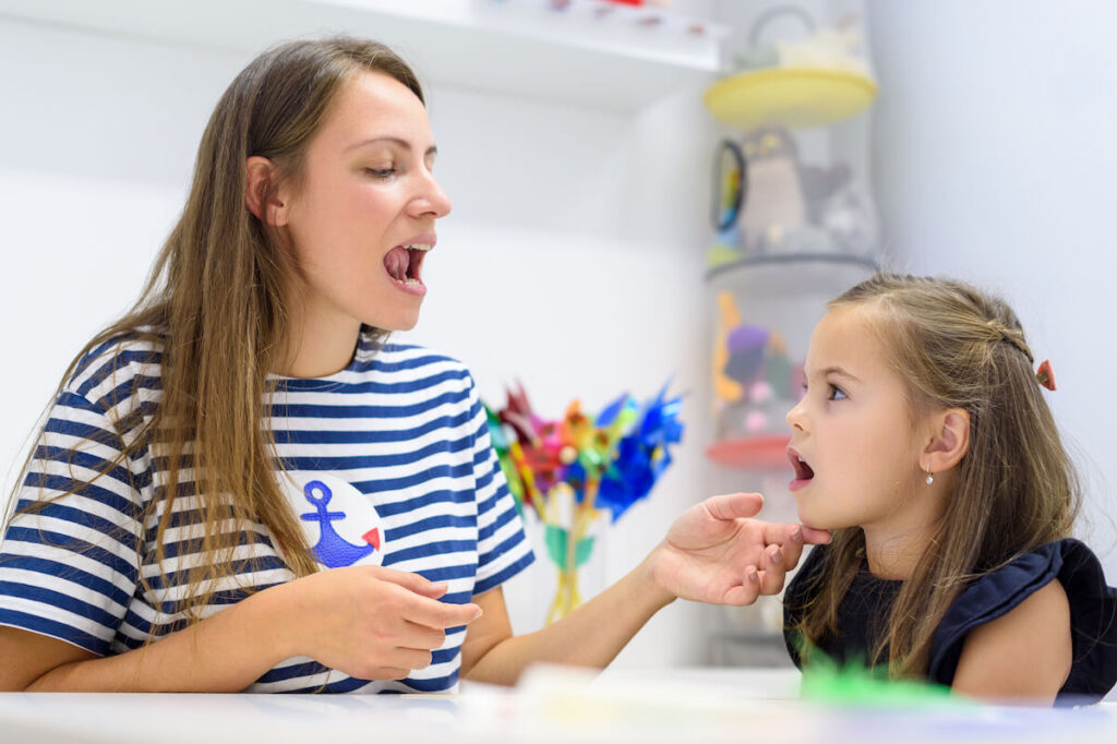 child practicing correct pronunciation with teacher