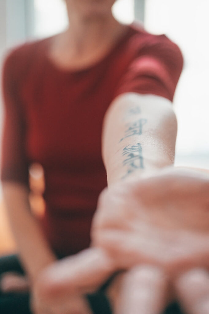 woman showing sanskrit tattoo on forearm