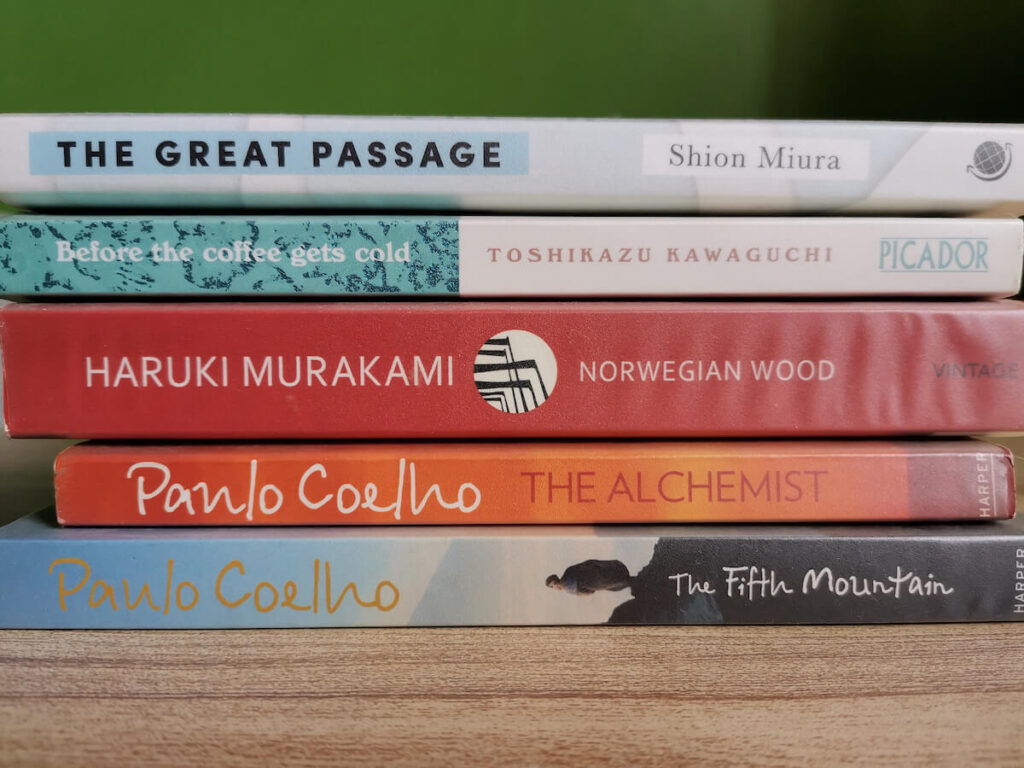 Stack of novel by Paulo Coelho, Haruki Murakami, Toshikazu Kawaguchi and Shion Miura translated into English