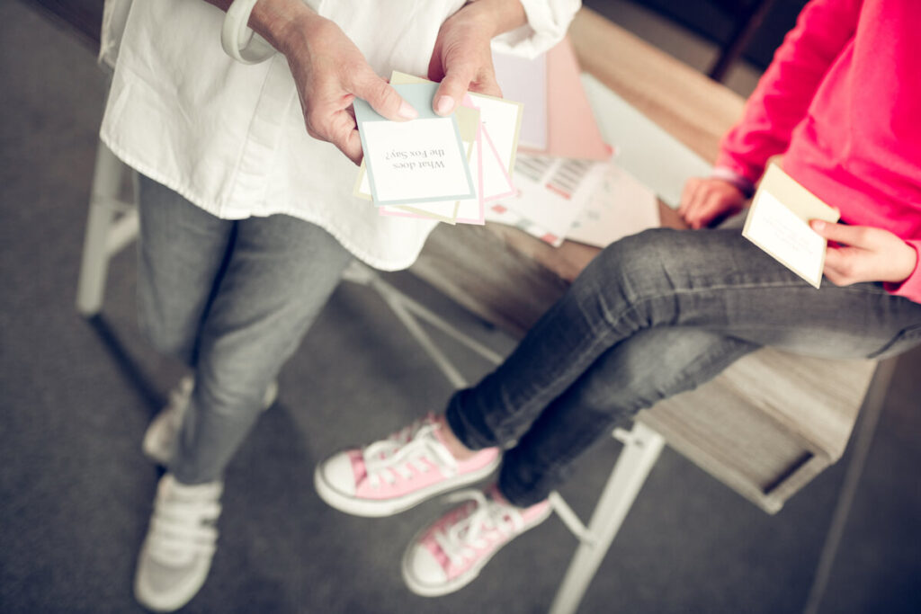 Close up of older woman and young girl holding flashcards while playing games together