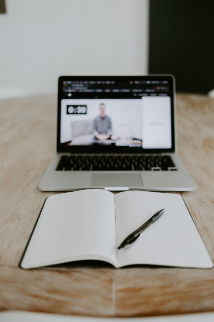 blank notebook and laptop showing online class