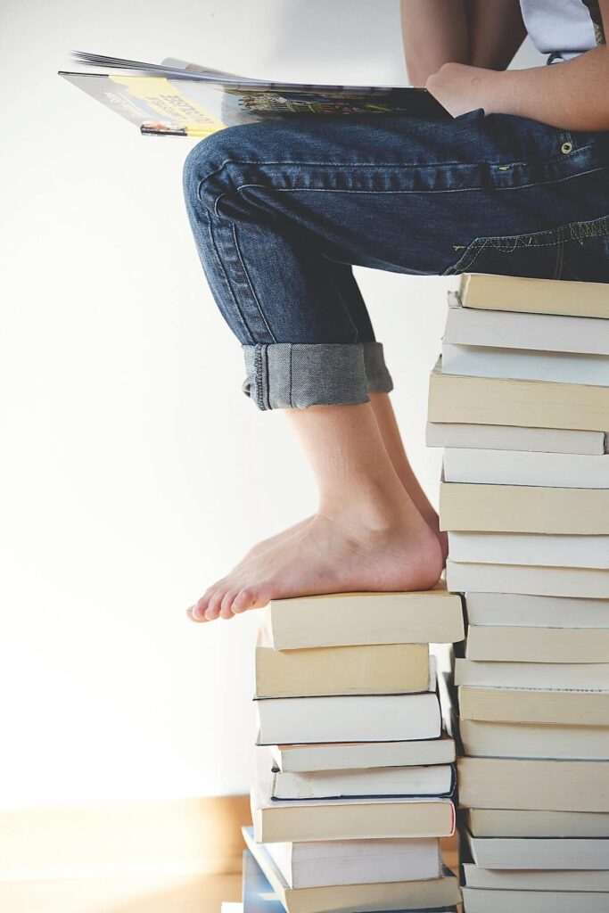 girl sitting on top of book stack