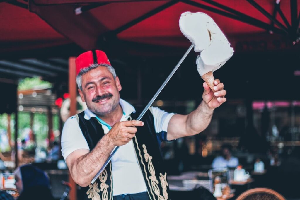 man smiling and holding stick with Turkish ice cream on cone
