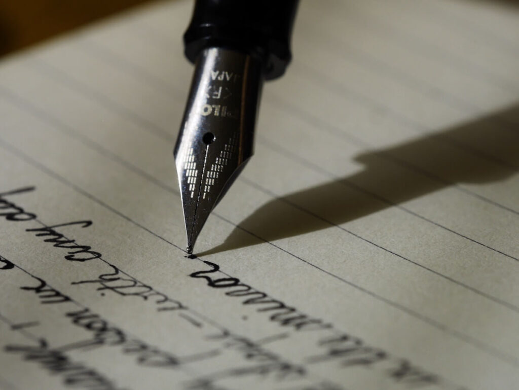 person writing with fountain pen