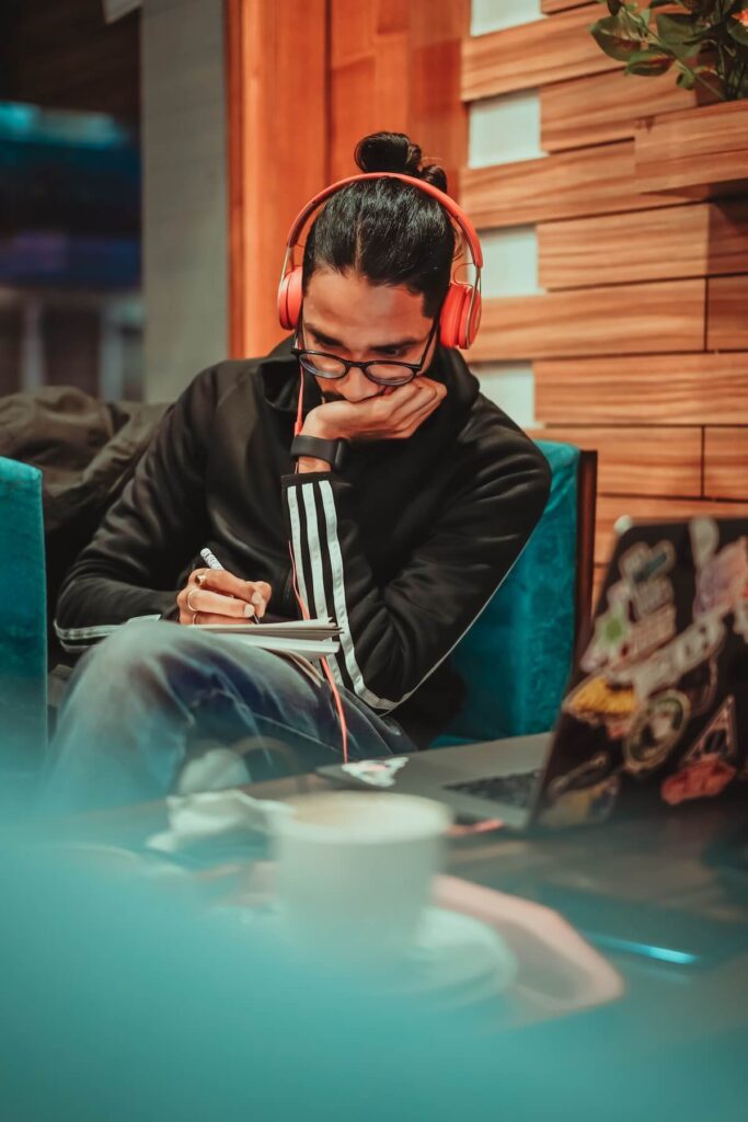 man writing with headphones on