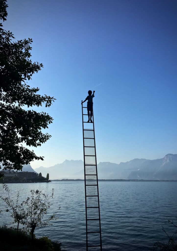 child on top of lakeside ladder