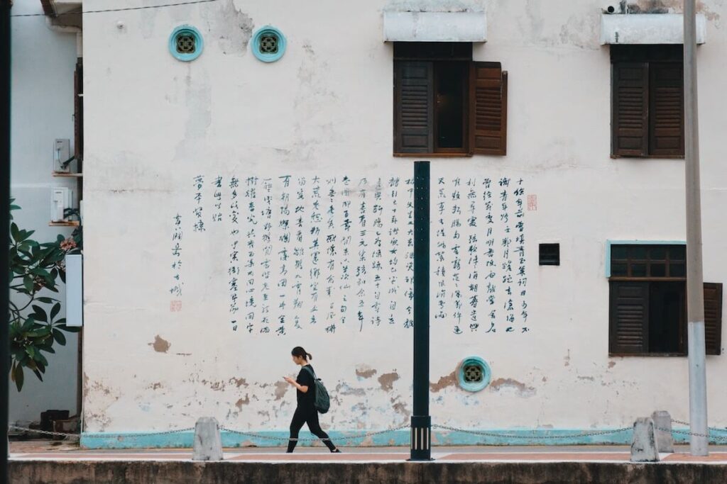 A girl walking by Chinese writing on a wall in Malacca, Malaysia